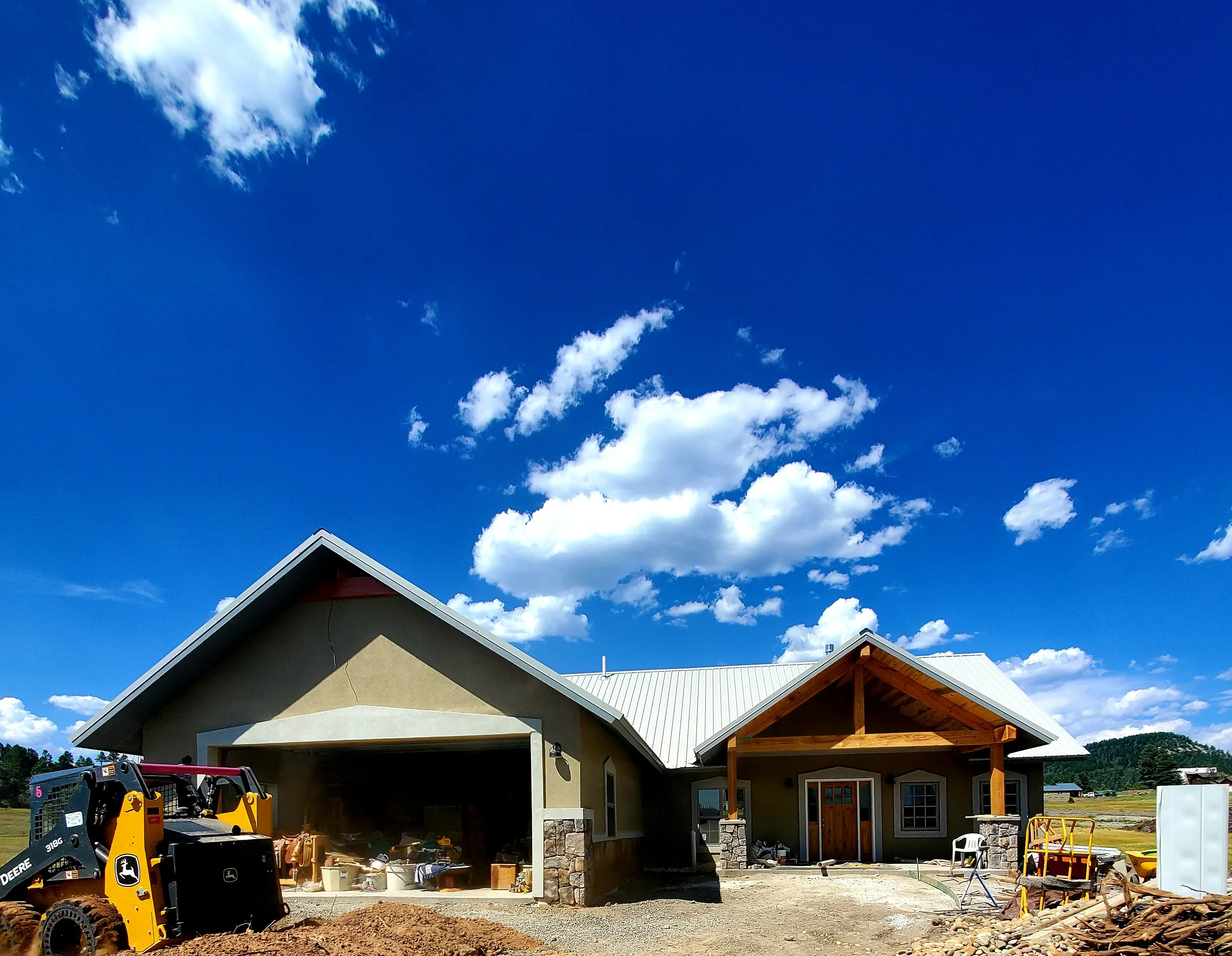 Residential home under construction with stucco garage, stone veneer, and metal roofing materials