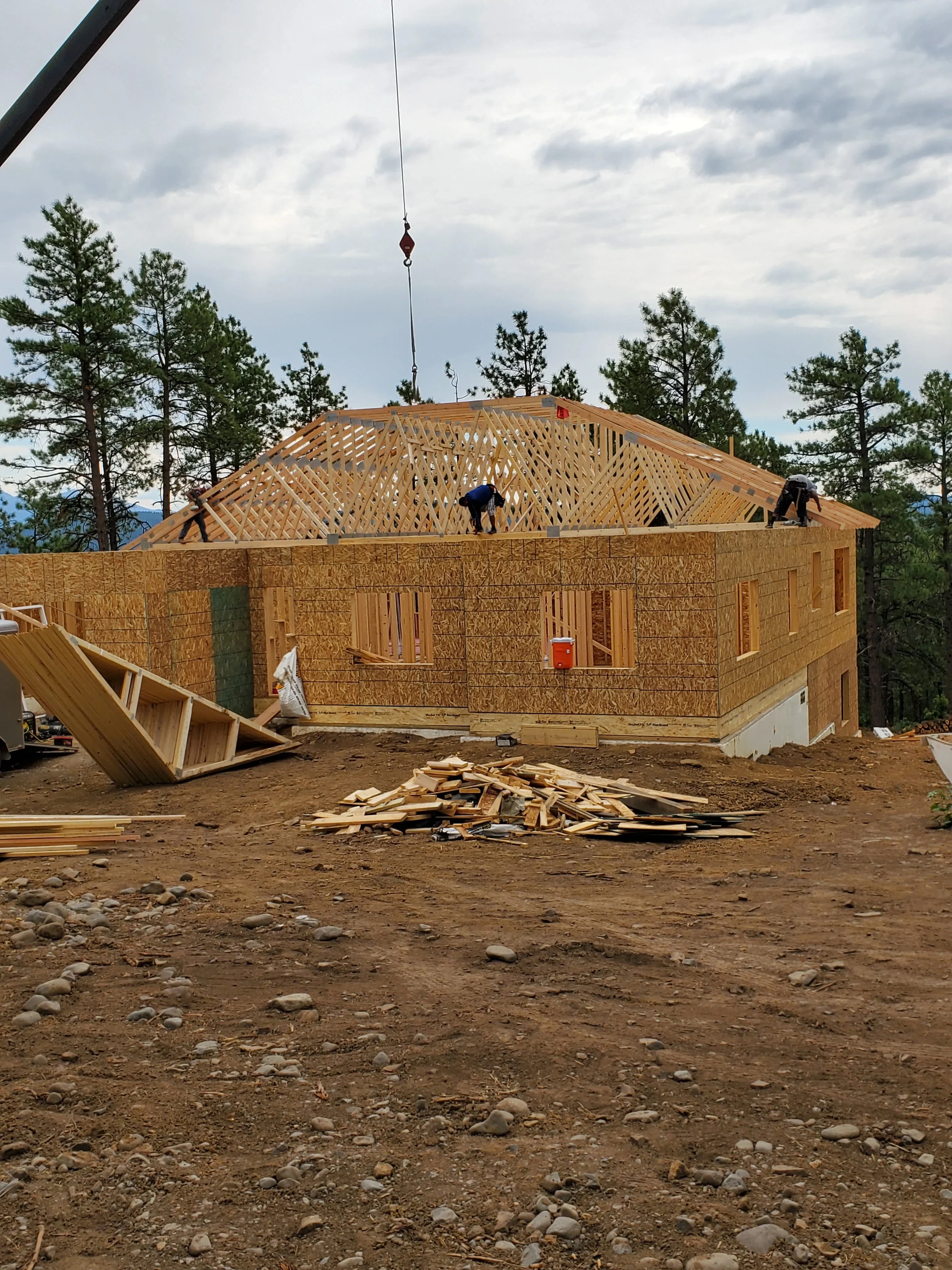 Residential home framing with engineered roof trusses, lumber walls, and OSB sheathing during active construction