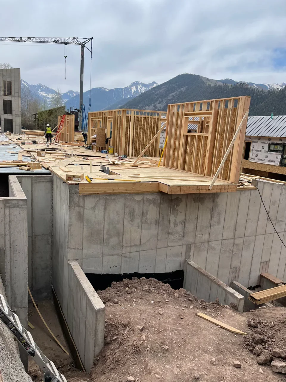 Wood stud framing walls and floor joists on concrete foundation with construction site equipment