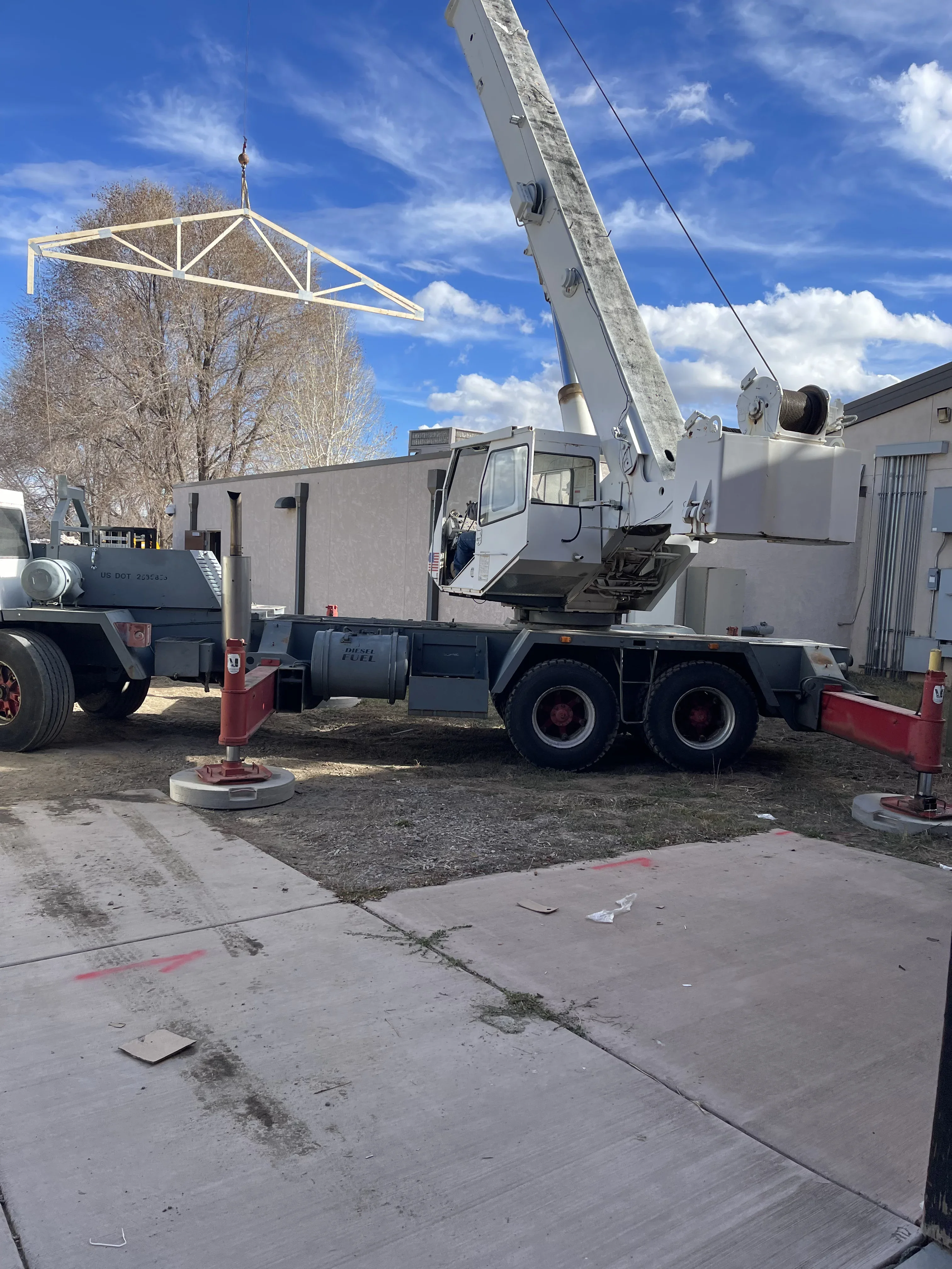 Mobile crane lifting steel roof truss with diagonal bracing during installation