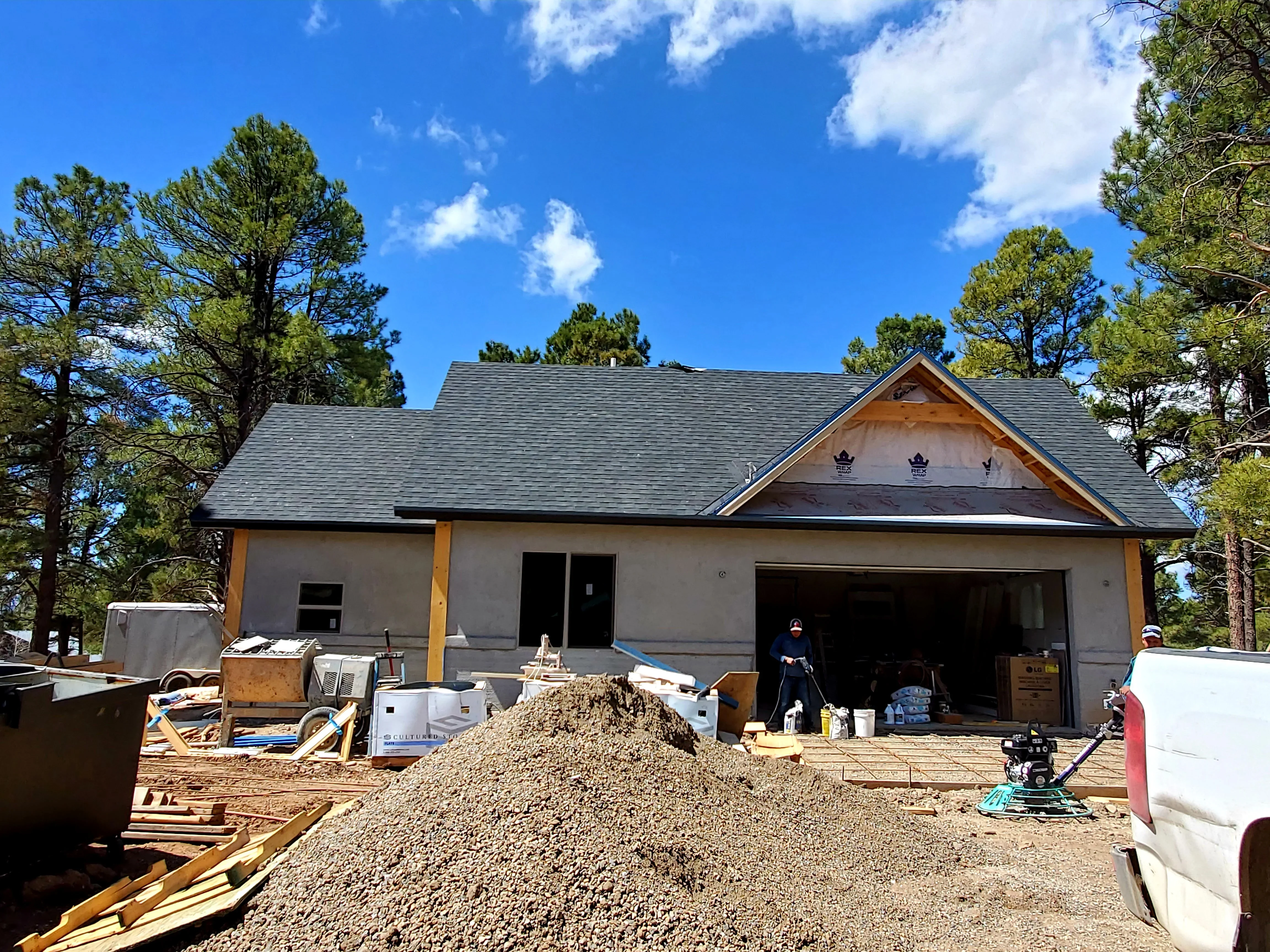 New home construction with stucco walls, gray roof, and open garage during active build phase
