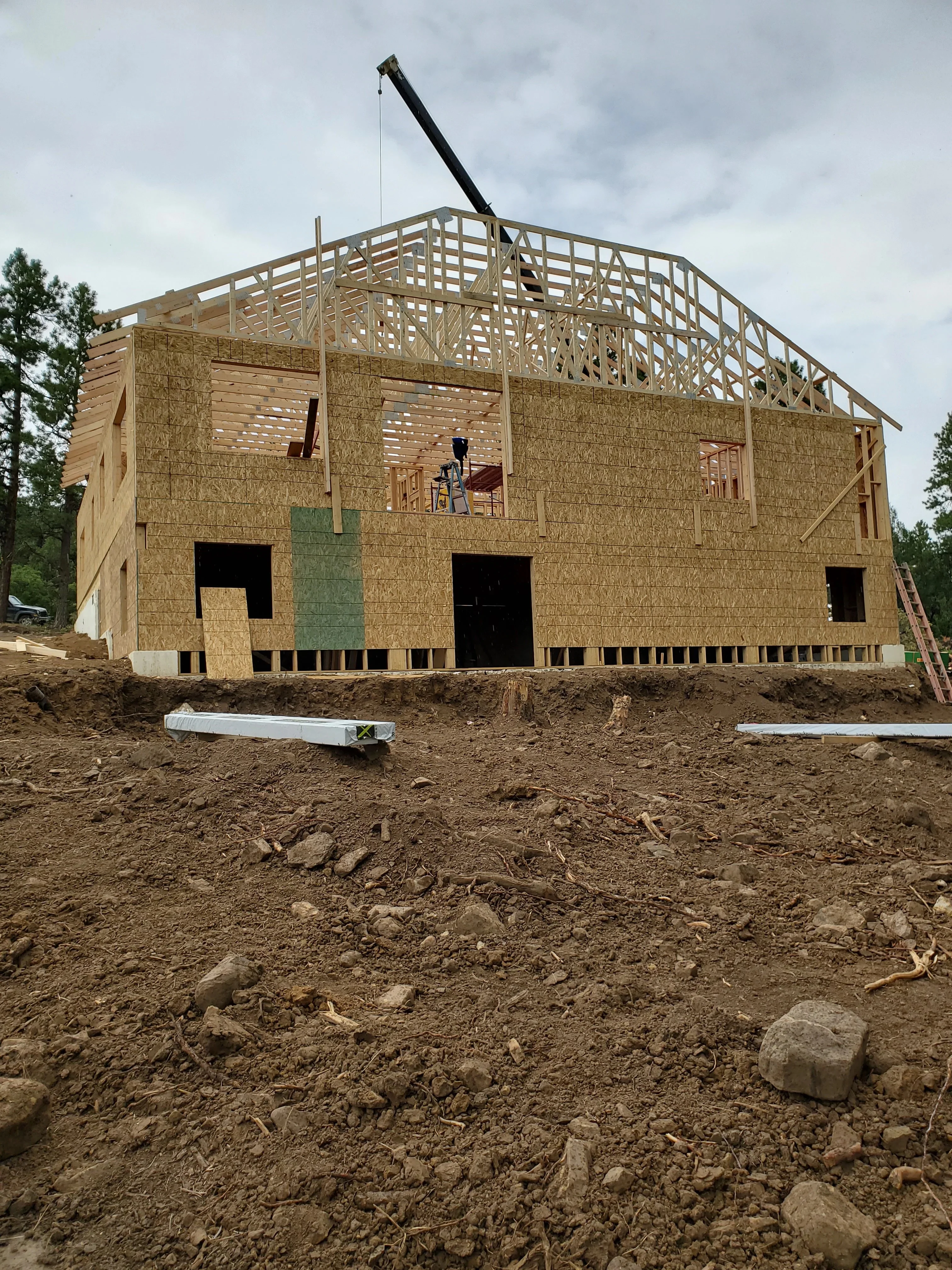 Two-story wood-framed house with OSB sheathing, roof trusses, and concrete foundation during construction phase