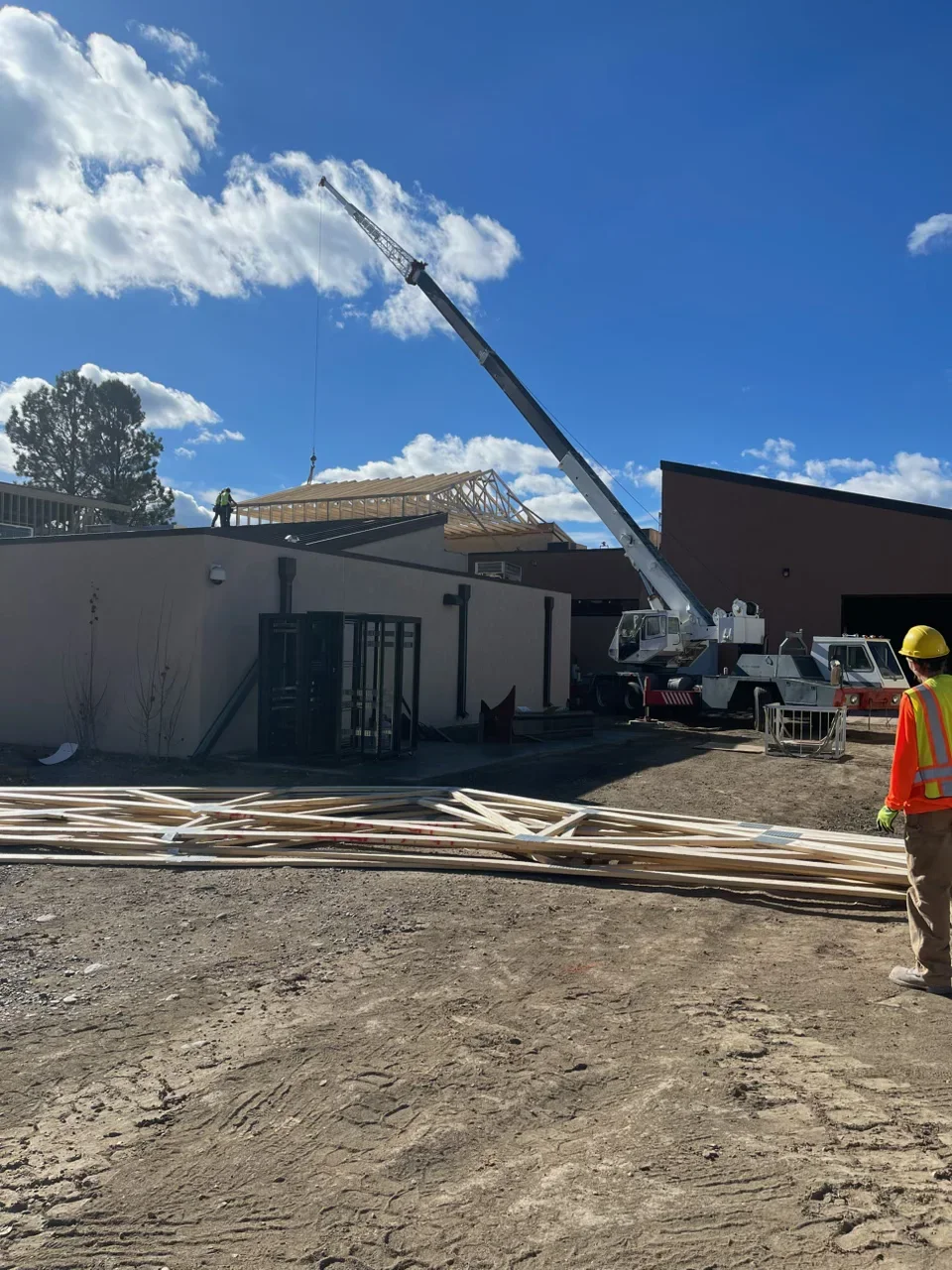 Mobile crane lifting engineered roof trusses onto commercial building frame