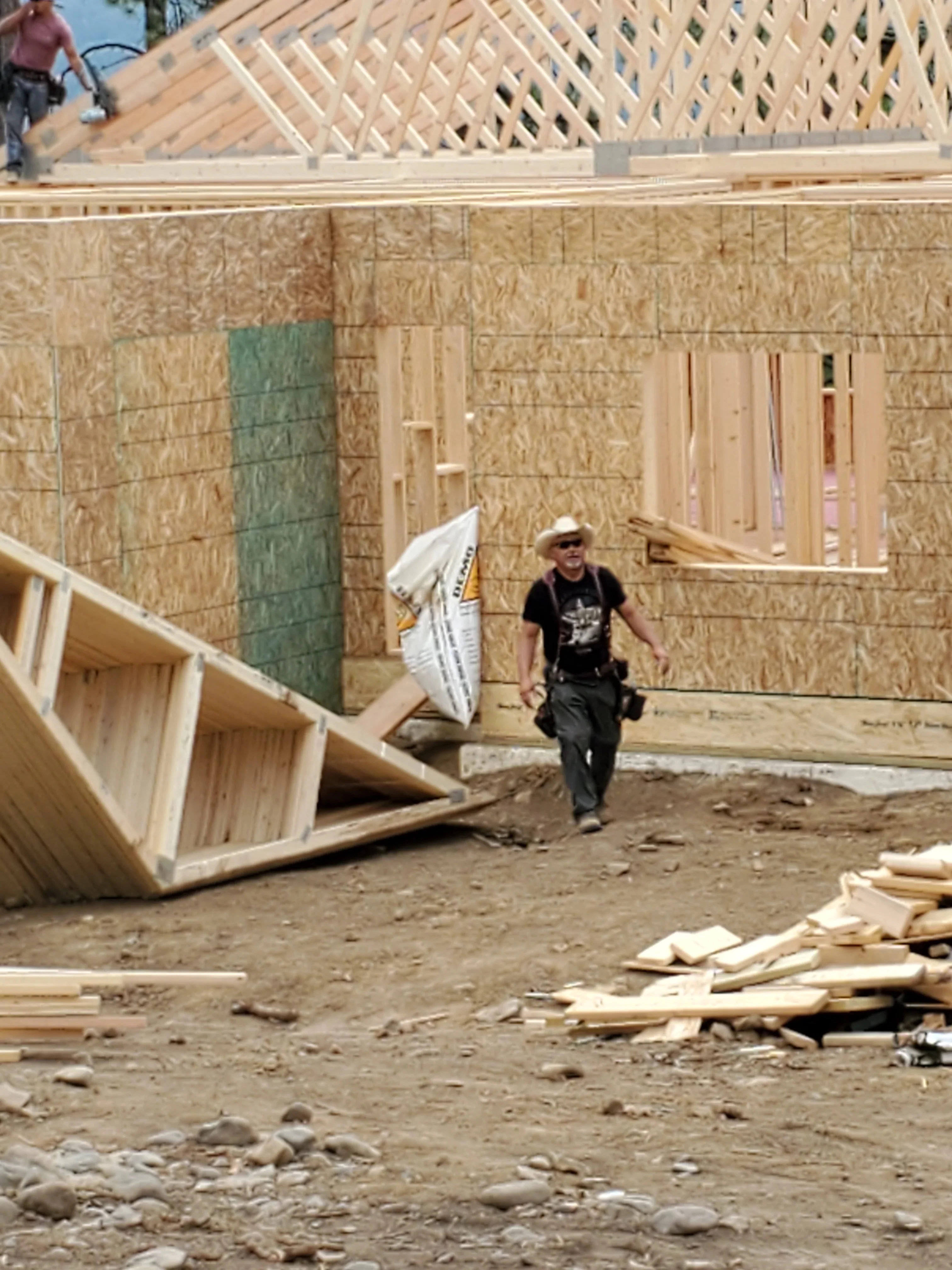 OSB sheathed exterior walls with exposed wood framing and roof trusses during construction