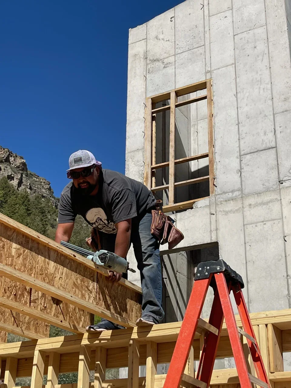 Worker installing wood framing on concrete panel building with window opening