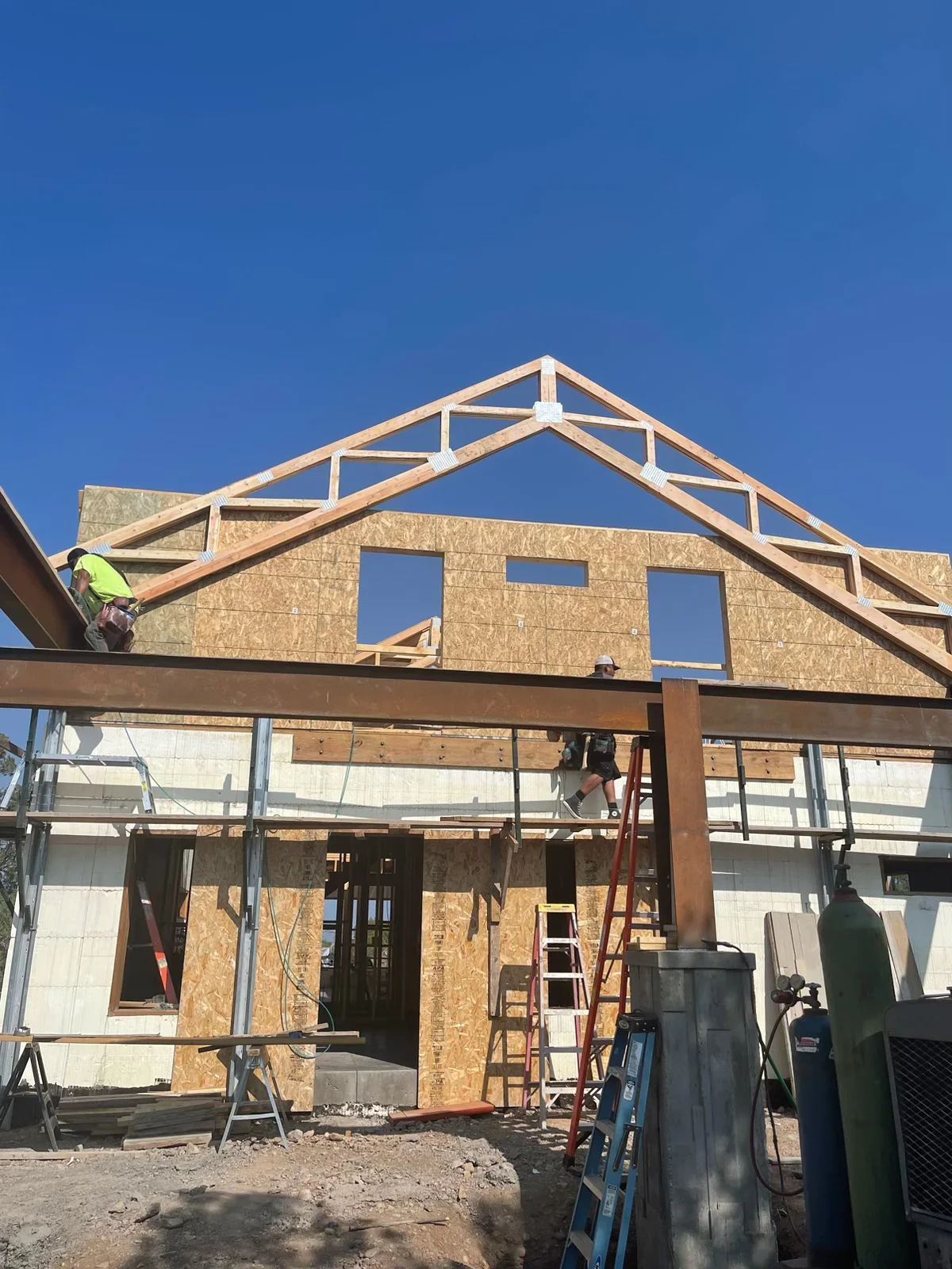 Residential home framing with engineered roof trusses, OSB sheathing, and window openings under construction