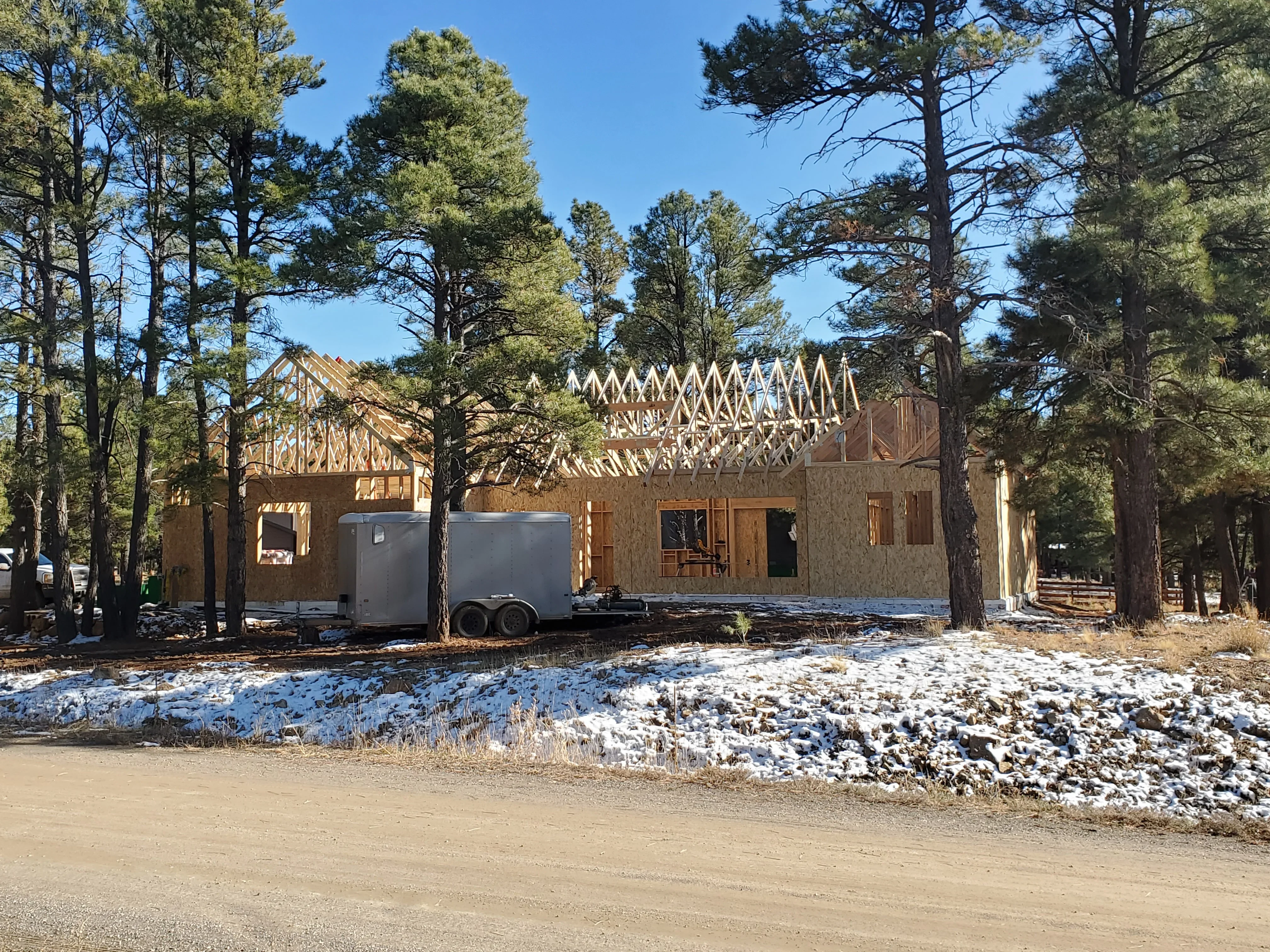Wood-framed residential structure with exposed roof trusses and OSB sheathing during construction phase