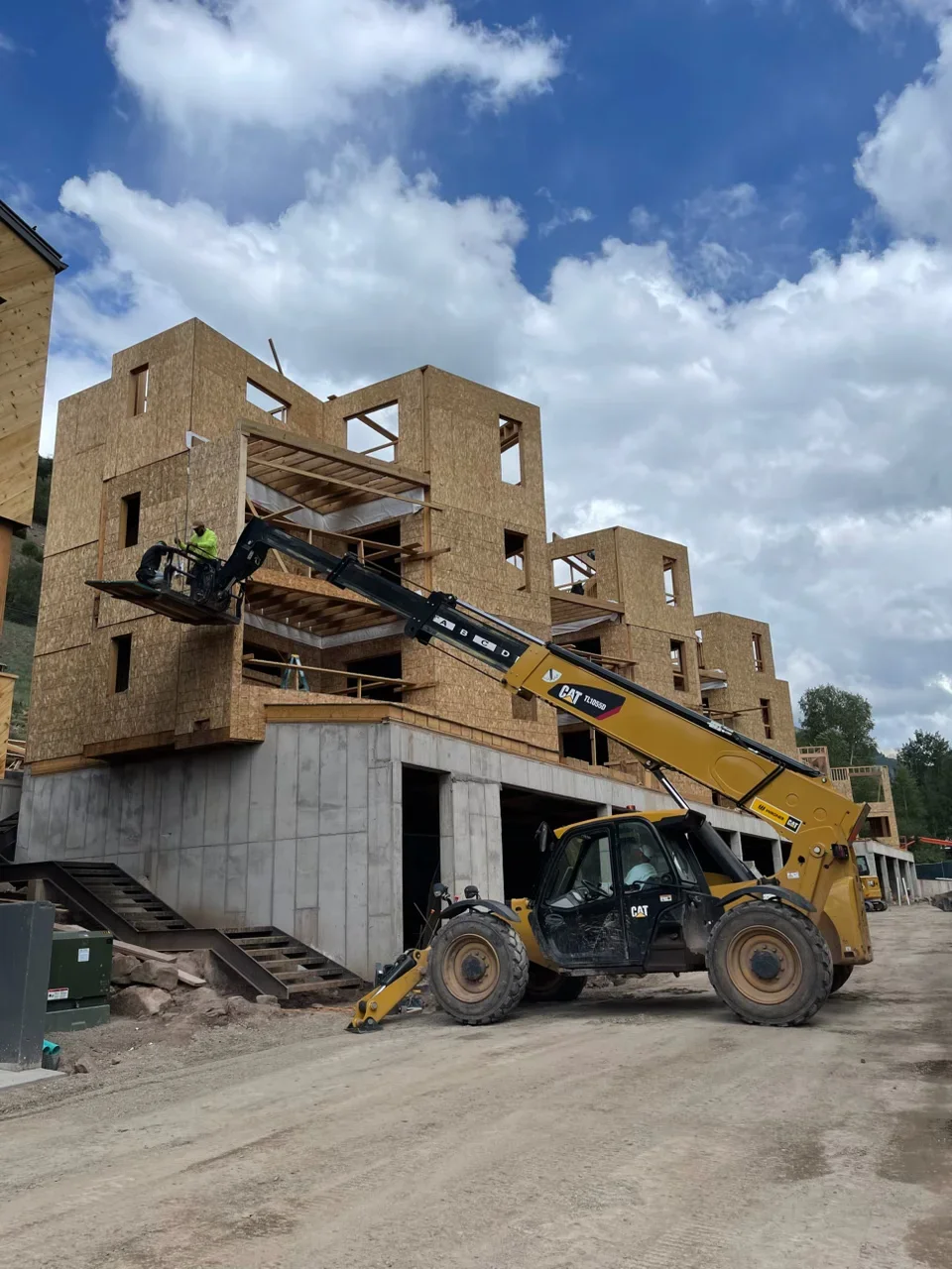 Three-story brick veneer residential buildings under construction with concrete foundation and steel framing